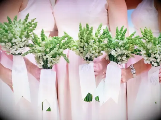 bridesmaids in pink dresses holding green snapdragon bouquets tied with monogrammed ribbon