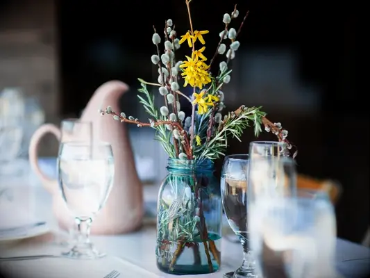 blue mason jar filled with pussy willow and yellow forsythia