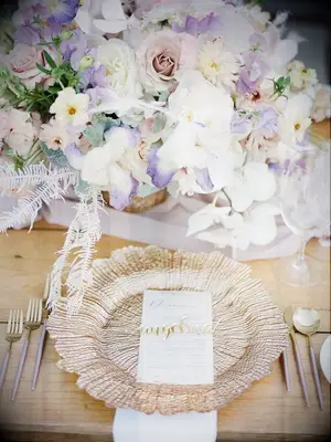 Gold place setting decorated with purple flower arrangement 
