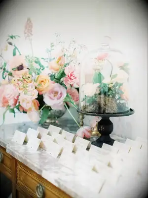 escort card table decorated with cloche-covered floral arrangement