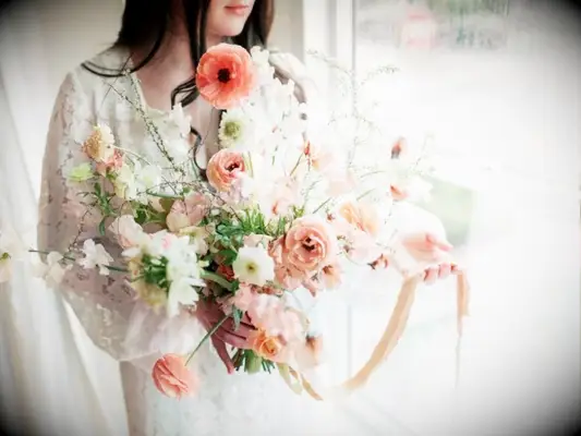 bride holding peach ranunculus bouquet