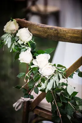 wedding idea for spring wooden cross back chair decorated with white roses and greenery