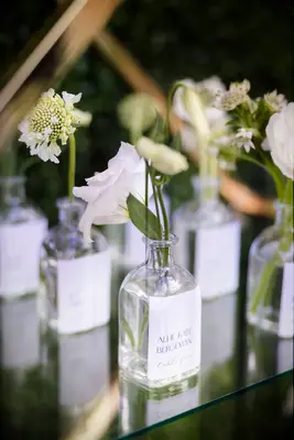 spring wedding escort card idea glass bud vase with a single white flower and label with guest name 