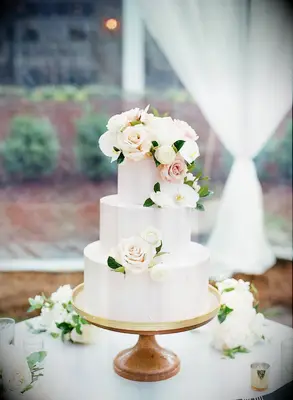 elegant three tier spring wedding cake decorated with pale pink buttercream, ivory flowers and pink roses
