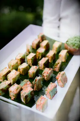 server holding a tray of bite sized shrimp sandwiches