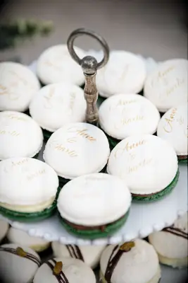 white macarons decorated with couple name written in gold calligraphy lettering