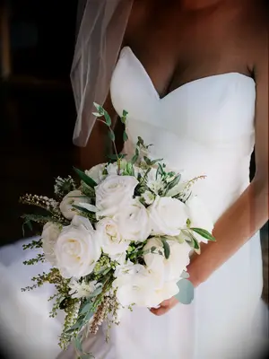 bride holding classic white wedding bouquet with roses, pieris japonica and eucalyptus