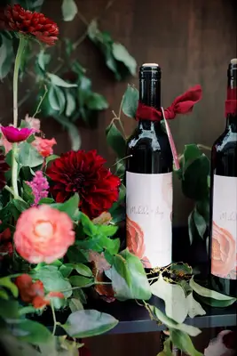 Custom wine bottle with escort card tag surrounded by flowers