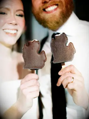 Couple holding chocolate-covered ice cream bars shaped like Michigan