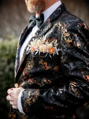 Groom wearing ornate suit jacket with flowers in breast pocket