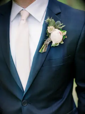 A gentleman wears a dusky blue tux with a boutonniere in pastel colors.