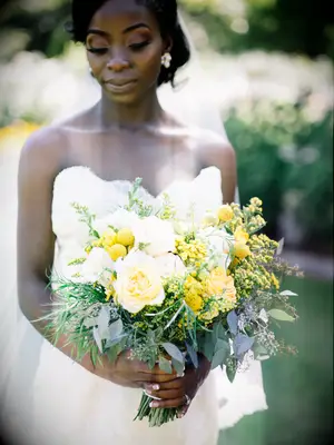 A bride walks down the aisle with a blooming bouquet in shades of vibrant yellow and brilliant white.