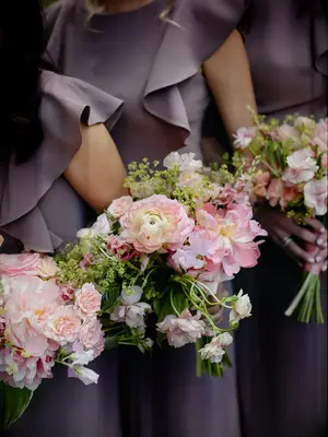 Bridesmaids hold pale pink and green bouquets.