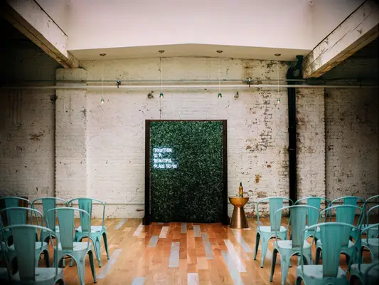 modern indoor wedding arch alternative with neon sign against boxwood wall