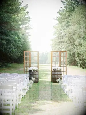 rustic outdoor wedding ceremony decor with wooden window panels and wine barrels at altar