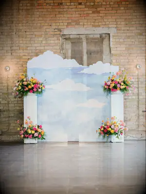 cloud wedding backdrop decorated with pink, yellow and orange flower arrangements