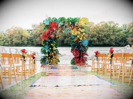 square wedding arch decorated with spray-painted monstera leaves in yellow, red and turquoise