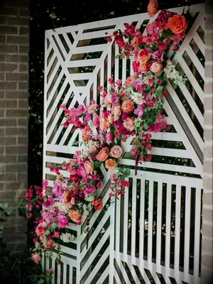 geometric wedding backdrop with pink, orange and red flowers diagonally across front