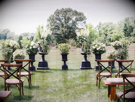 outdoor wedding ceremony altar with white flowers potted in urns