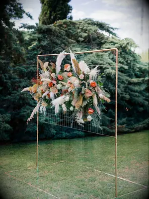 boho wedding arch alternative with pampas grass, eucalyptus, and orange roses arranged on metal grid screen