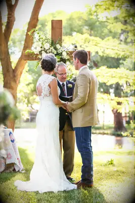 Bride and groom have Christian ceremony with wooden cross. 