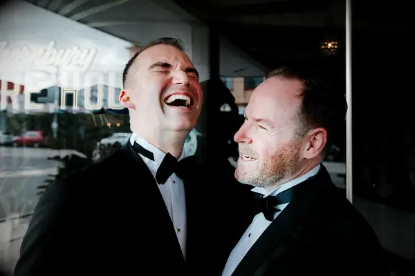 Grooms laughing together after the wedding.