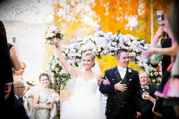 A bride and groom walk hand and hand back down the aisle in a Jewish wedding ceremony