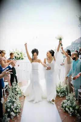 Two brides walk hand in hand down the aisle in Amalfi