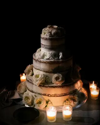 classic three tier semi naked wedding cake with white roses and votive candles