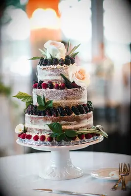 three tier semi naked wedding cake with blackberries, raspberries and white roses