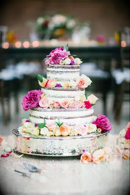 three tier chocolate semi naked wedding cake decorated with pink, fuchsia and peach roses
