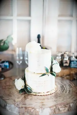 simple two tier semi naked wedding cake with vanilla sponge, white chocolate drip icing and white roses 