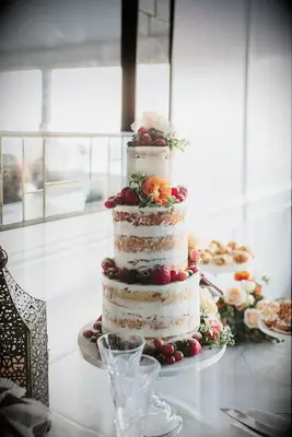semi naked wedding cake with strawberries, red grapes, and orange flowers