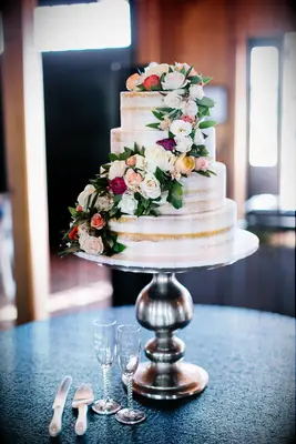 three tier semi naked wedding cake with cascading spray roses on silver cake stand