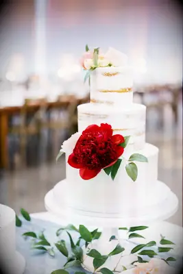 white wedding cake with bottom fondant tier and two tiers with semi naked frosting decorated with red peony