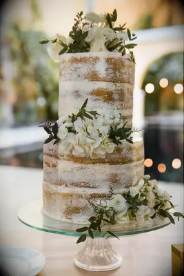 two tier vanilla semi naked wedding cake decorated with white flowers and greenery