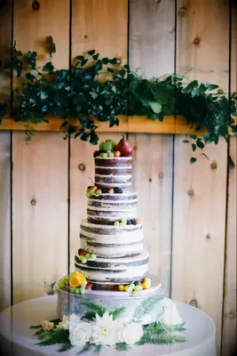 four tier chocolate semi naked wedding cake with grapes, apples and sliced oranges