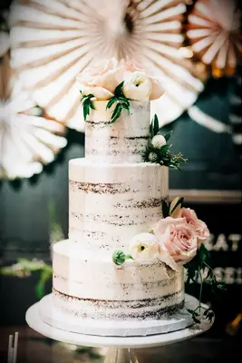 three tier semi naked wedding cake with blush roes and white ranunculus