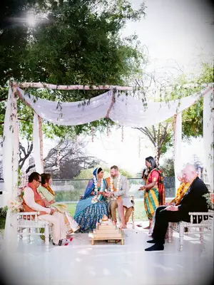 Couple and parents underneath simple wood mandap