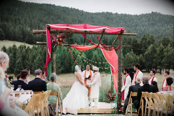 Couple exchanging vows beneath wood mandap in the mountains