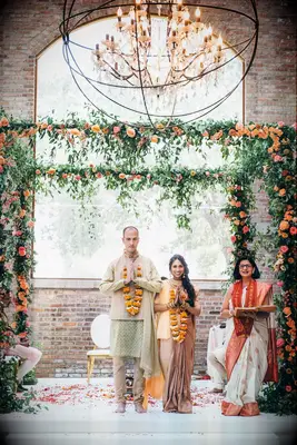 Couple standing under green-and-orange mandap
