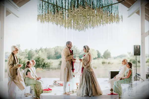 Couple under modern mandap with hanging flowers