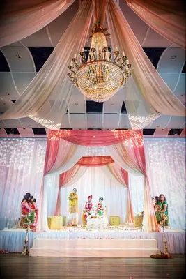 Mandap in hotel ballroom with crystal chandelier and fabric draping