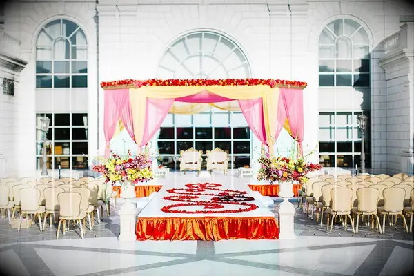 Glam pink-and-orange mandap with petal-lined aisle