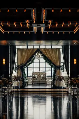 Mandap with cream draping and greenery garland accents