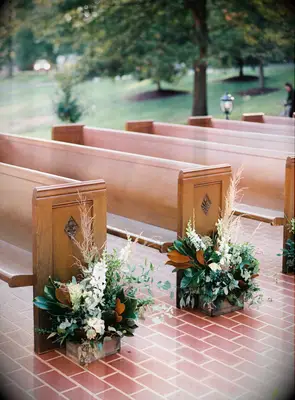 Wood pews accented by magnolia leaf arrangements