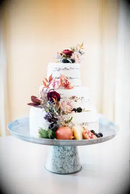 Semi-naked buttercream wedding cake with flowers and pomegranates