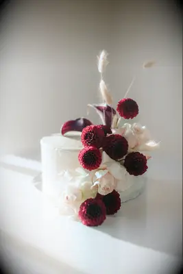 One-tier cake with fresh burgundy dahlia and cally lily blooms.