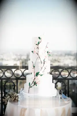 Modern white wedding cake with cherry blossom decorations