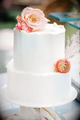 White two-tier wedding cake with fresh flowers